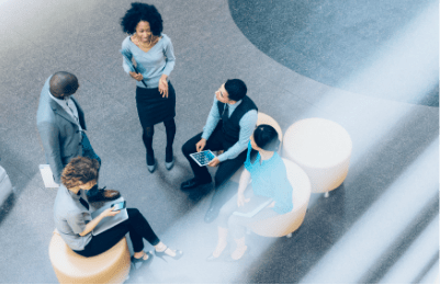 An overhead view of three women and two men as they talk together in an office lobby.